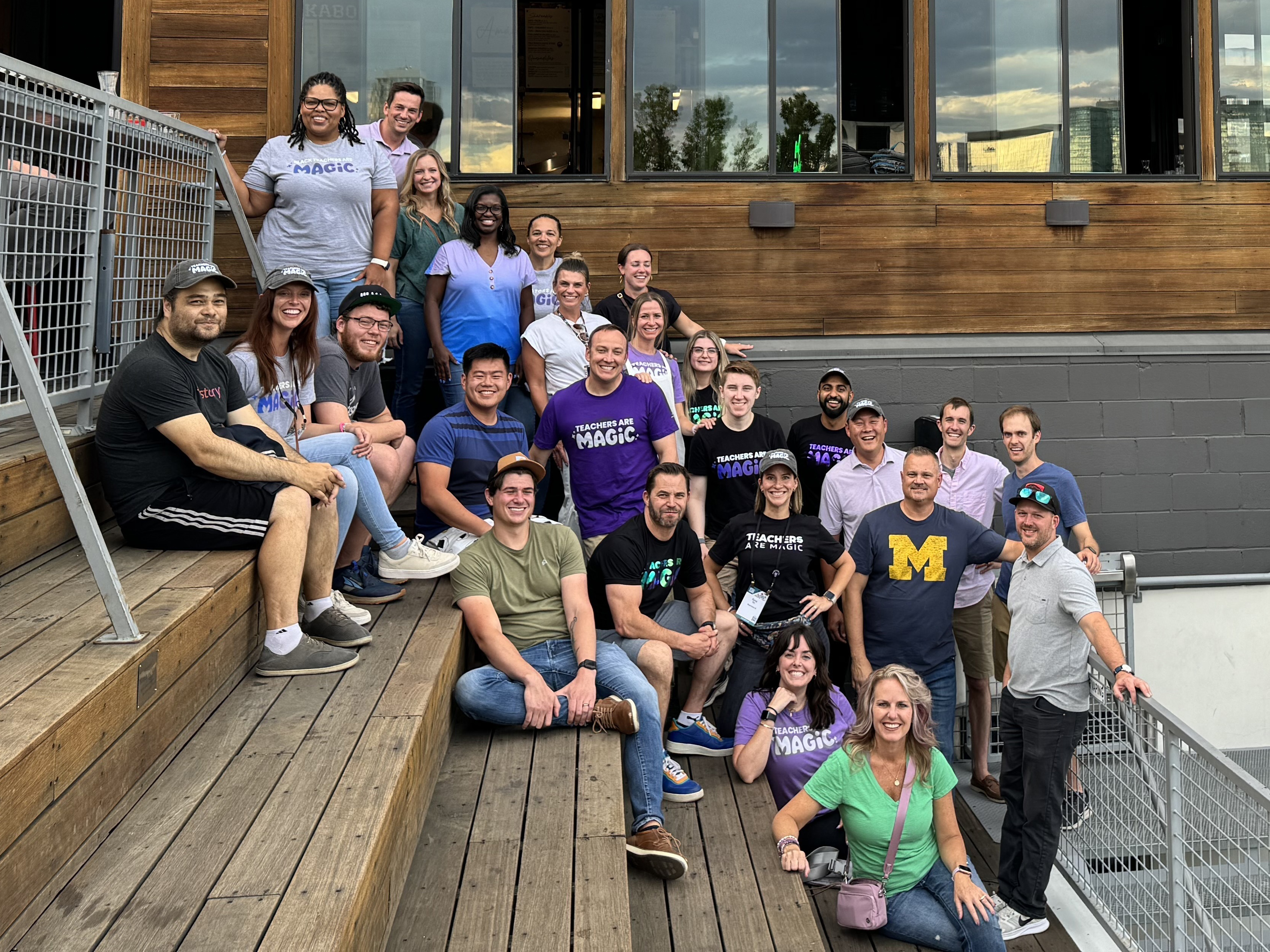 Group of MagicSchool employees posing for team photo on wooden stairs